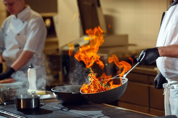 Modern kitchen. Cooks prepare meals on the stove in the kitchen of the restaurant or hotel. The fire in the kitchen.