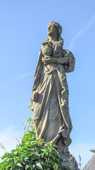 Wall Mural - Stone monument of a woman with a bowl in her hands on a background of blue sky