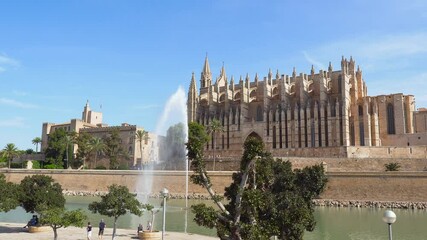 Wall Mural - Pan over Cathedral (La Seu) and Royal Palace (Almudaina) in Palma de Mallorca with pond and fountain in the foreground - Spain