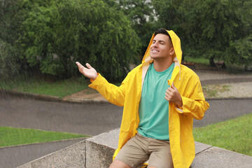 Wall Mural - Man with raincoat walking under rain in park