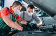 © davit85 - A masked mechanic checks the car at the service station.