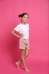 Wall Mural - Cute girl in pajamas on pink background