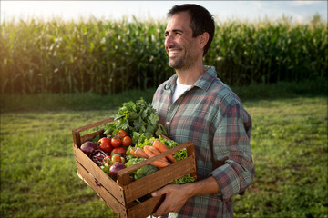 Authentic shot of happy smiling male farmer walking with basket with fresh harvested at the moment vegetables  on countryside field. Concept: biological, bio products, bio ecology, vegetarian, vegan