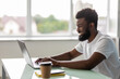 © F8  \ Suport Ukraine - Handsome Afro American man is using a laptop and smiling while working in office