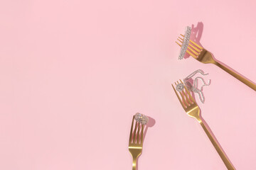 Wall Mural - Creative  layout with golden forks, ring, earring and hairpin with gemstones on pastel pink background. Luxury aesthetic fashion concept with jewelry. Retro 80s or 90s minimal food idea. 