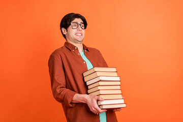 Sticker - Photo of young happy smiling funky funny guy college student hold heavy books wear glasses isolated on orange color background