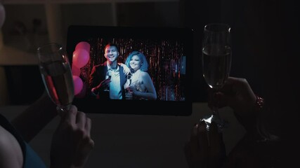 Wall Mural - Web party. Digital New Year. Holiday video conference. Internet congratulation. Happy couple greeting friends with Christmas drinking champagne using tablet at festive night.