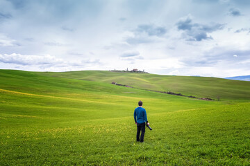 Wall Mural - an alone photographer with camera in hands enjoys the amazing spring landscape in the heart of tusca