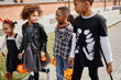 © Seventyfour - Group of excited African-American kids wearing Halloween costumes outdoors while trick or treating together