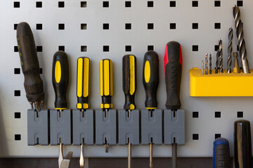 Screwdrivers, drill bits and tools nicely placed in repair shop wall. Industry work equipment concept