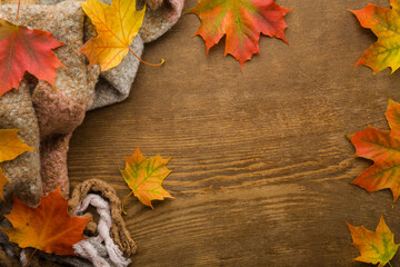 Wall Mural - Fresh colorful maple leaves and soft scarf on brown wooden table background. Closeup. Autumn concept. Empty place for inspirational text, quote or sayings. Top down view.