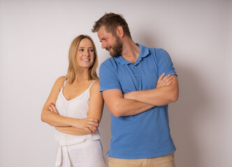 Wall Mural - Portrait of caucasian couple man and woman in casual clothing smiling at each other standing with arms crossed isolated over white background