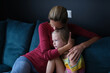 © H_Ko - Woman and sad little daughter are sitting on couch and hugging