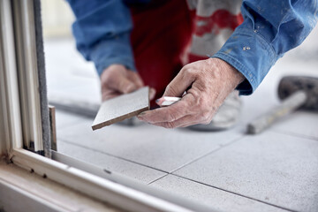 Wall Mural - Professional ceramics tile man worker placing new tiles on the floor and wall.