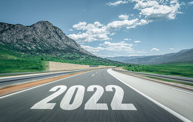 2022 New Year road trip travel and future vision concept . Mountain landscape with highway road leading forward to happy new year celebration in the beginning of 2022 for successful start .