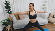 © mojo_cp - Portrait of gorgeous young asian woman practicing yoga at home stretching out while following a yoga routine