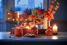Two Orange Cups  Of Tea And Autumn Decor With Pumpkins, Flowers And Burning Candles On Table