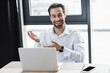 positive businessman pointing with hands near laptop and smartphone with blank screen in office