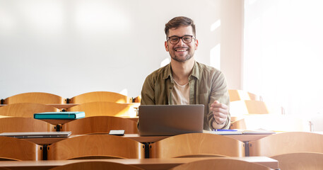 portrait of young male university student sitting in classroom and preparing for lecture. educationa