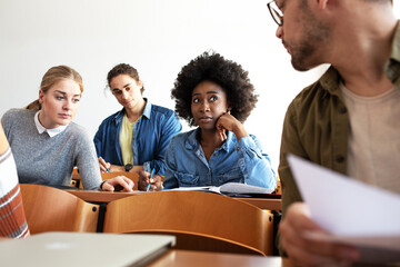 Wall Mural - Group of college students working on test in a classroom. Black female student lookong serious and trying to resolve problem.
