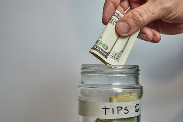 man's hand handing over a hundred dollar tip