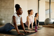 © Drazen - Black female athlete warms up while doing stretching exercise on group training at gym.