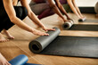 © Drazen - Close-up of athletic women roll their exercise mats after sports training in gym.