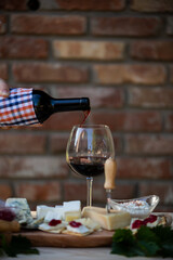 Poster - Bottle of red wine pouring into wineglass on the dining table