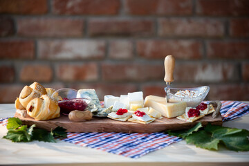 Sticker - Wooden board with various kinds of cheese, bread, ad jam on the table