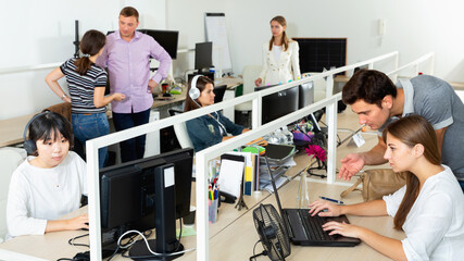 Wall Mural - Smiling positive people working with computers and laptops in modern office