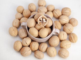 Aufkleber - A lot of whole walnuts in a cup on a white background close-up. Healthy, organic food with a high content of protein and protein.