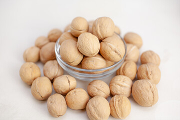 Aufkleber - A lot of whole walnuts in a cup on a white background close-up. Healthy, organic food with a high content of protein and protein.