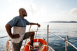 © fotofabrika - Young african american man relaxing on a sailboat in open sea at sunset