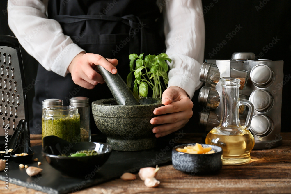 Woman preparing tasty pesto sauce on table
