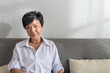 © tai - Close-up portrait of an attractive middle-aged mature grey-haired Asian woman posing at home in the morning, elder female sitting on a sofa in the living room. Positive single senior retired Concept
