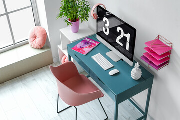 Workplace with modern computer and stylish decor near white wall in light room