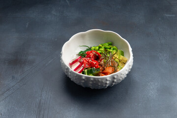 Poke with salmon, beans and radishes in a plate. On a gray background.