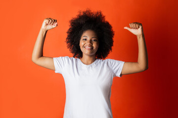 Wall Mural - beautiful african woman in white t-shirt with raised arms on red background 