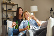© djile - Two young beautiful women sitting on sofa drink beer and using a smartphone