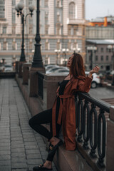 Wall Mural - Stylish young brunette woman in fashionable long brown leather coat. Autumn street style. Casual fashion. Copy, empty space for text