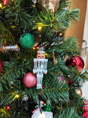 Toy glass soldier and colourful Christmas balls hanging on the Christmas tr