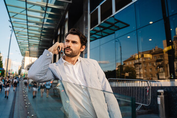 Young man wearing jacket talking on mobile phone on city street