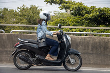A Young Woman Riding A Motorcycle On Road. Asian Girl Rides Scooter In The Street.