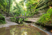 Family Hiking Outdoors Across A Bridge In The Forest Near Hocking Hills State Park In Ohio
