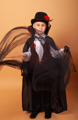 Wall Mural - Boy 8 years old in the costume of Count Dracula vampire And up throw a piece of fabric on a beige background with space for the text