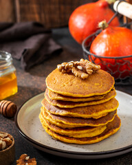 Wall Mural - Pumpkin pancakes in a ceramic plate on a dark background close-up	