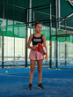 © RODRIGO - a beautiful young caucasian teenage girl in pink shorts and a black tank top practicing paddle tennis on an indoor court in summer