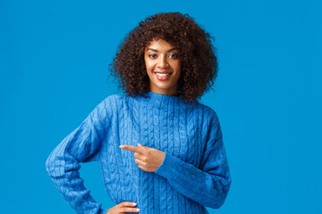 Wall Mural - Good deal right over corner. Confident pleasant friendly-looking african american gorgeous woman with afro haircut, asking check-out, visit store page, pointing finger left and smiling looking camera