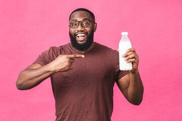 portrait of young african american black man holding bottle of milk isolated over pink background. h