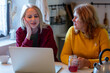 © Simonforstock - mother-in-law with a woman surfing Internet on laptop in kitchen of house